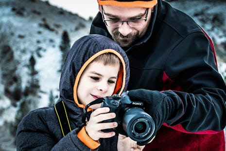 A father shows his son how to use a camera.