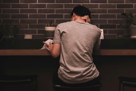 Young man reading a book at a coffee bar.